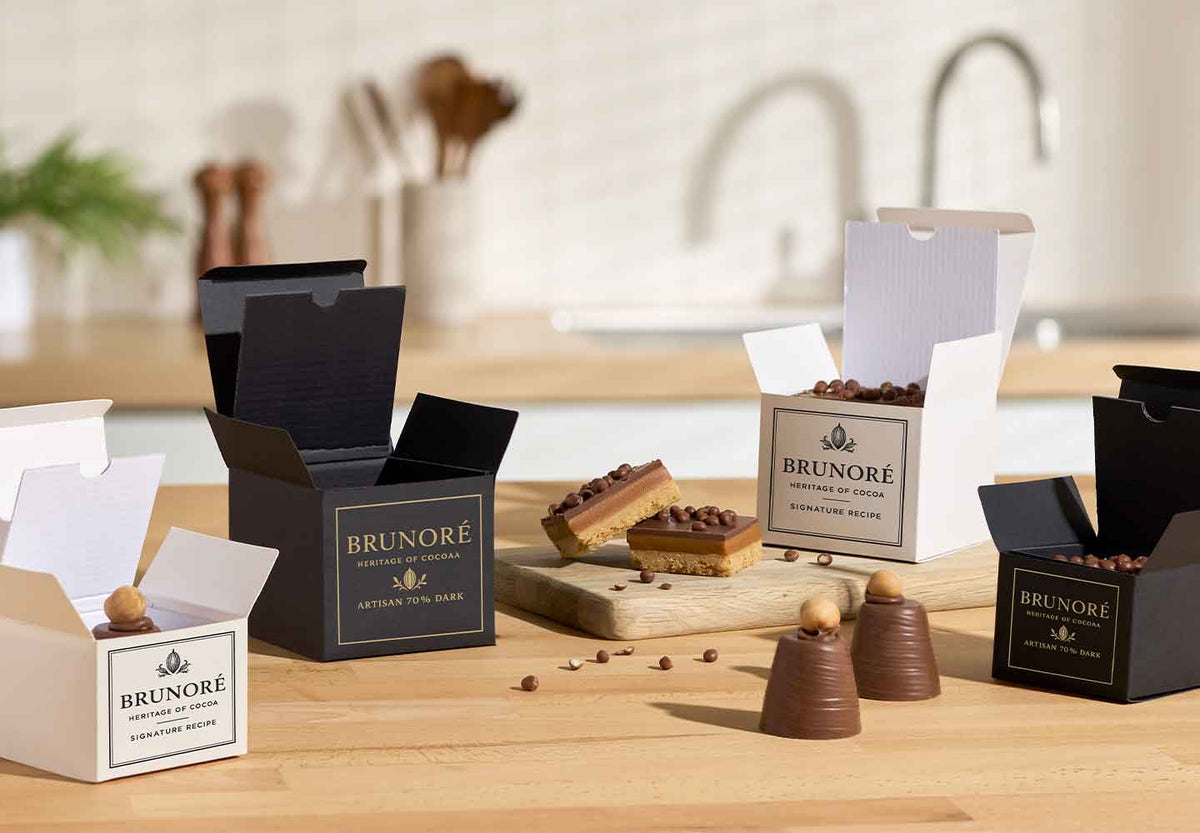 Selection of gift box packaging in black and white with cakes in kitchen.