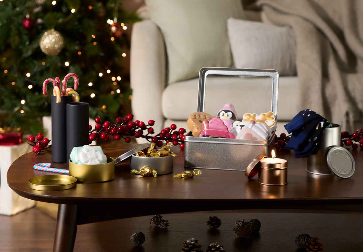 Decorative packaging on a table with a Christmas tree and sofa in the background