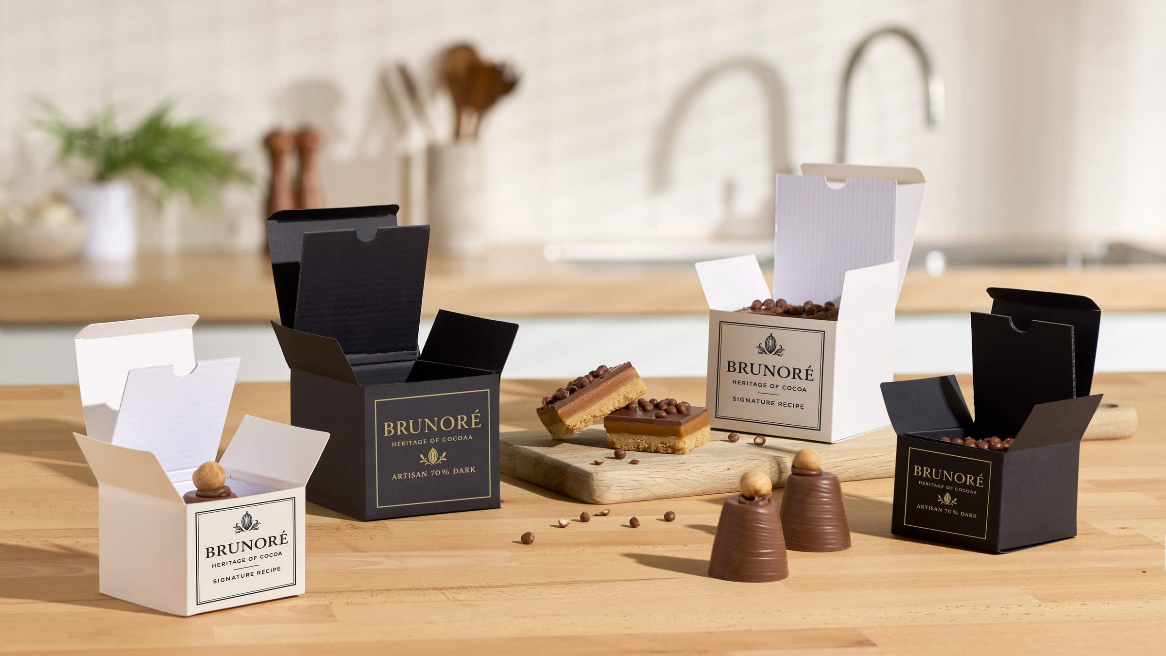 Selection of gift box packaging in black and white with cakes in kitchen.